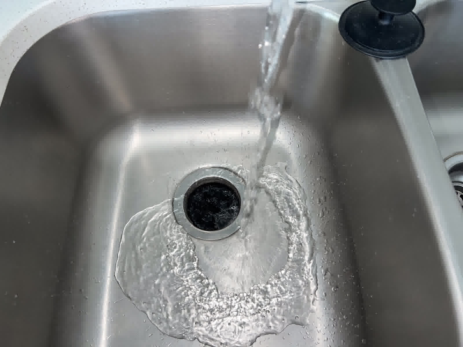Kitchen sink with running water from a modern faucet and a garbage disposal